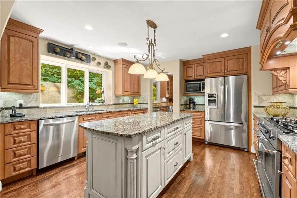 Kitchen featuring a center island, wood-type flooring, backsplash, and appliances with stainless steel finishes