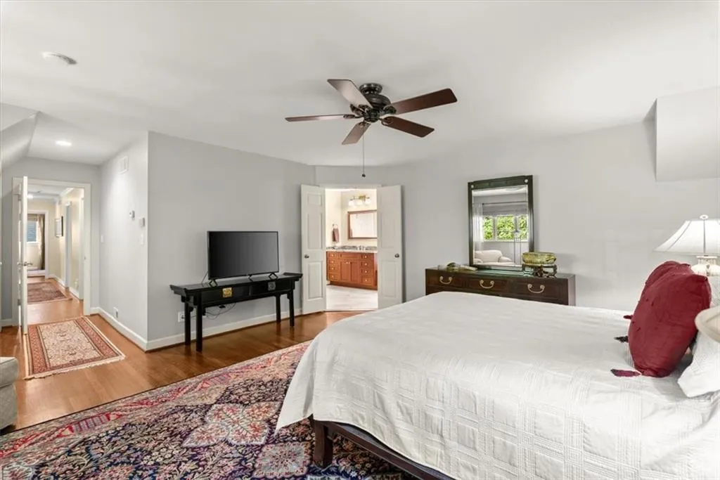 Bedroom featuring hardwood / wood-style flooring, ceiling fan, and ensuite bath