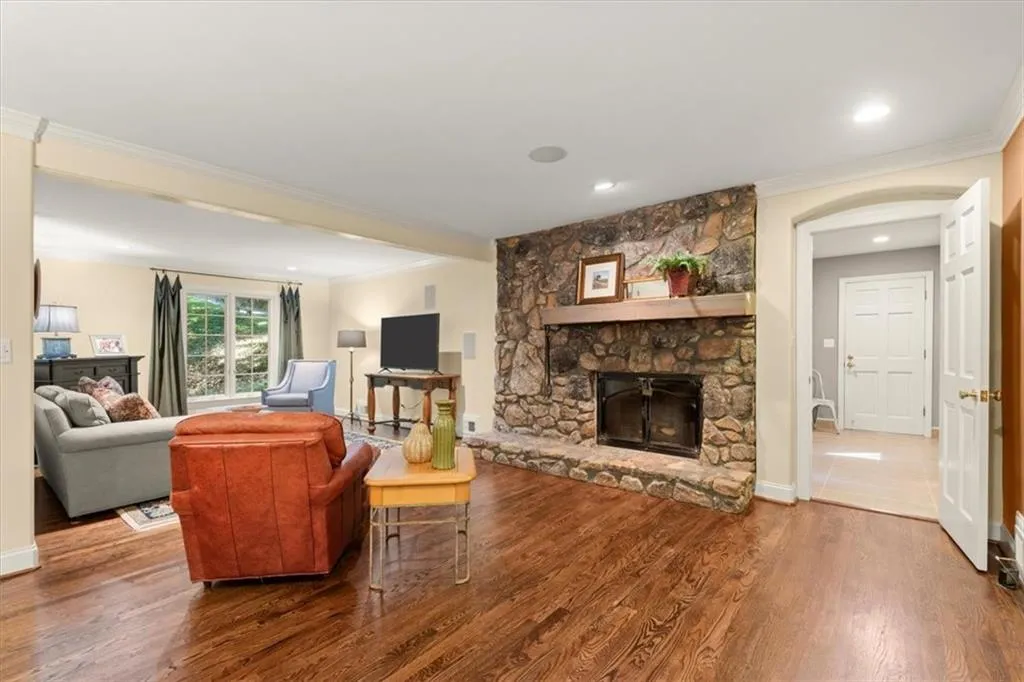 Living room with hardwood / wood-style floors, a stone fireplace, and ornamental molding
