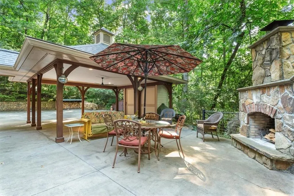 View of terrace with an outdoor stone fireplace and a gazebo