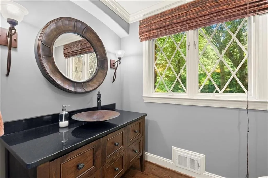 Bathroom with plenty of natural light, vanity with extensive cabinet space, and crown molding