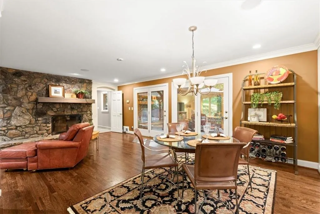 Dining area featuring crown molding, a stone fireplace, hardwood / wood-style floors, and a notable chandelier