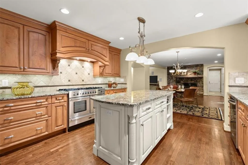 Kitchen with double oven range, tasteful backsplash, hardwood / wood-style floors, and premium range hood