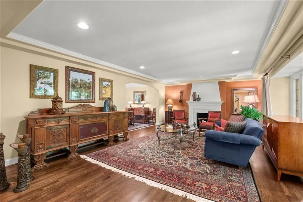 Living room with a large fireplace, a tray ceiling, hardwood / wood-style floors, and crown molding