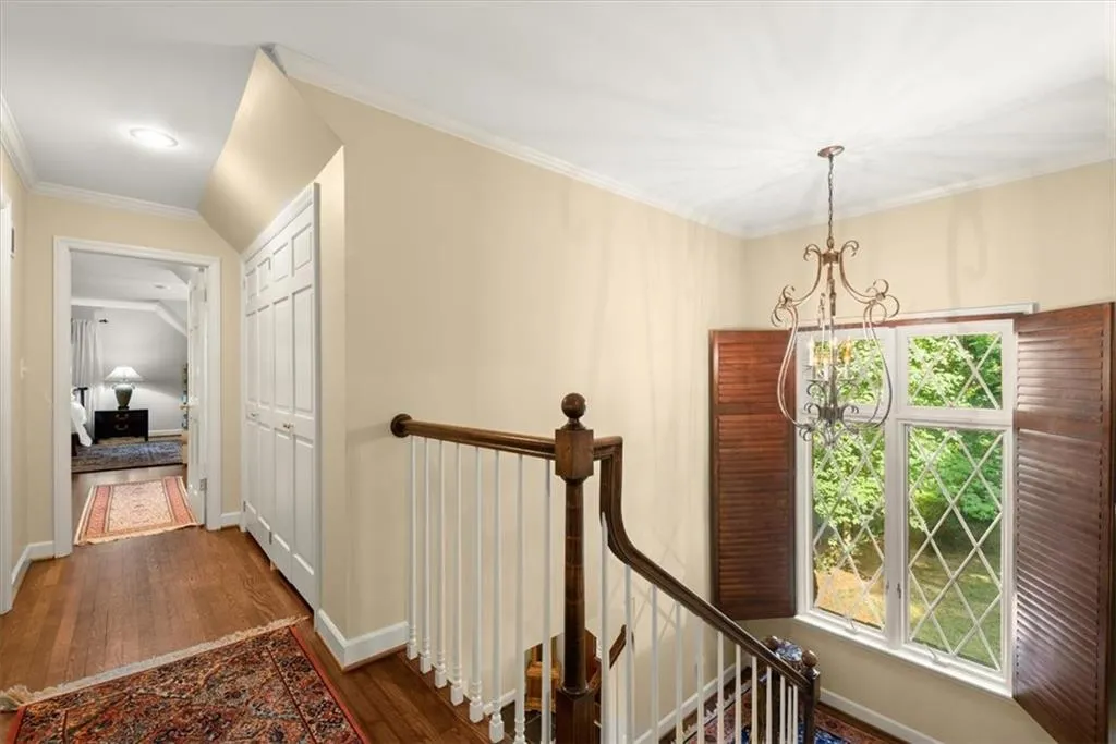 Hallway with dark hardwood / wood-style floors, a notable chandelier, and crown molding