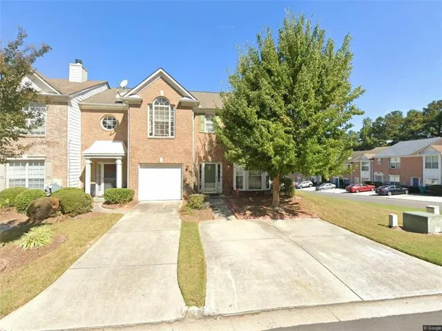 Brick exterior with white trim, arched window accents, attached garage, and concrete driveway