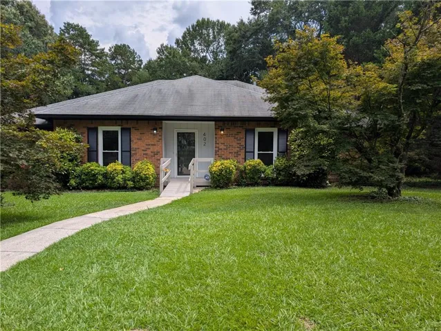 Brick exterior featuring a gray shingle roof, black louvered shutters, and white trim