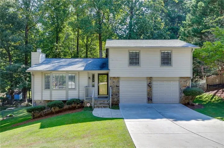 Front view showing the concrete driveway, garage, and entryway steps.