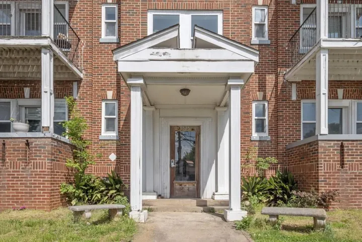 Brick exterior with white window trim and a columned entry porch