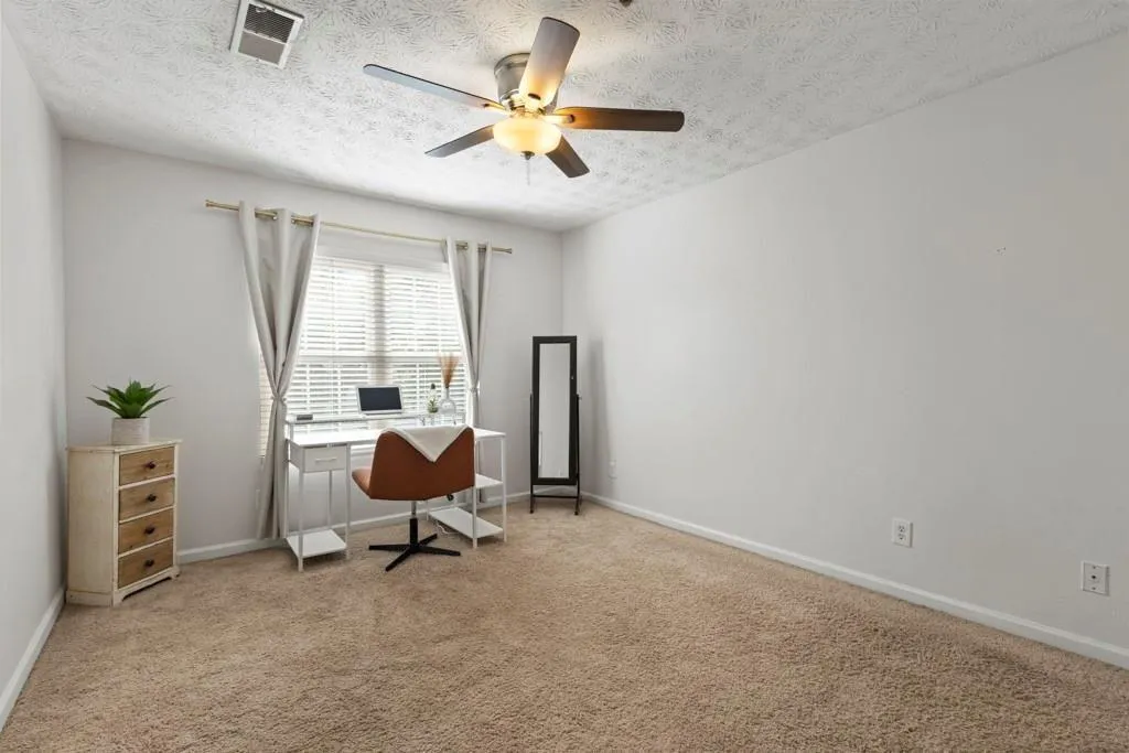 Office space with visible vents, a ceiling fan, li
