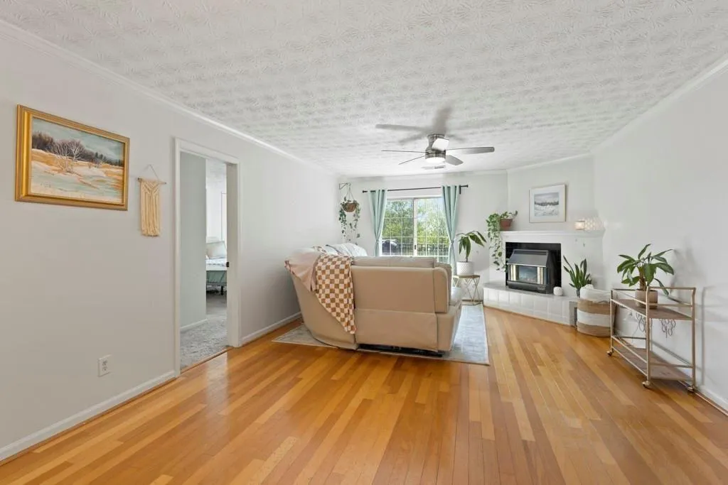 Living area with a tiled fireplace, a ceiling fan,