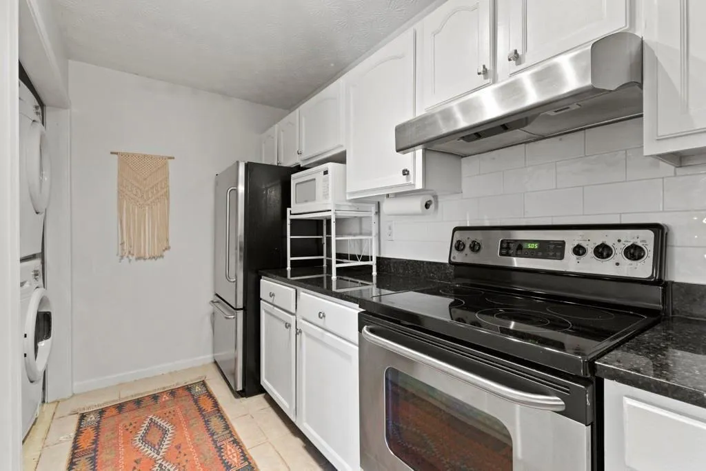 Kitchen featuring white cabinets, stacked washer /