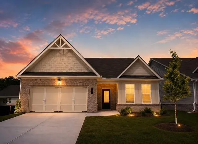 Single-story residence featuring a two-car garage, brick and siding exterior, gabled roofline, and established front landscaping