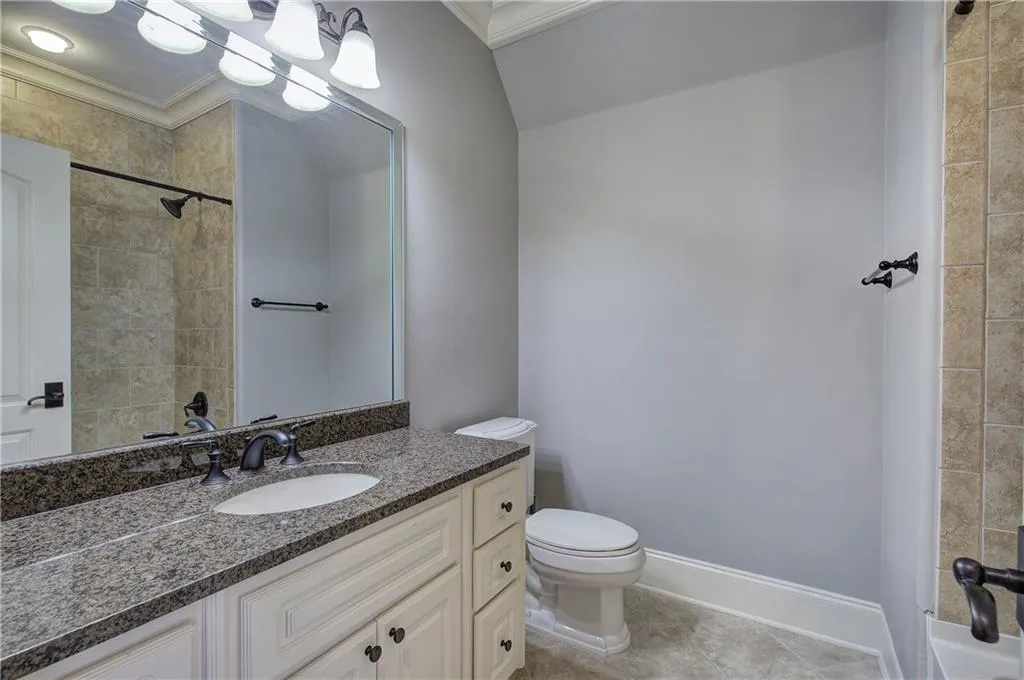 Bathroom featuring vanity, crown molding, tiled shower, and light tile patterned flooring