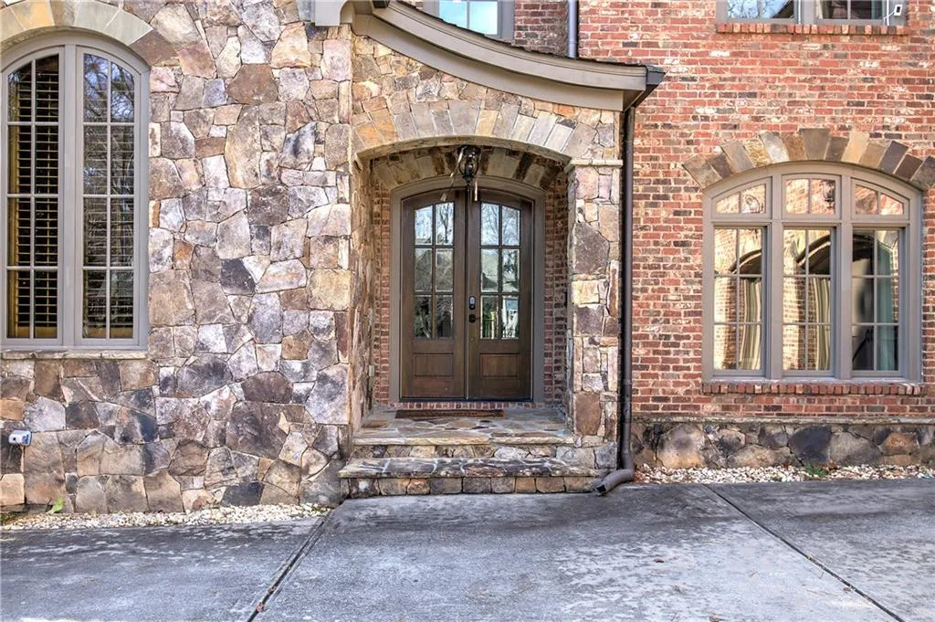 Doorway to property featuring brick siding, stone siding, and french doors