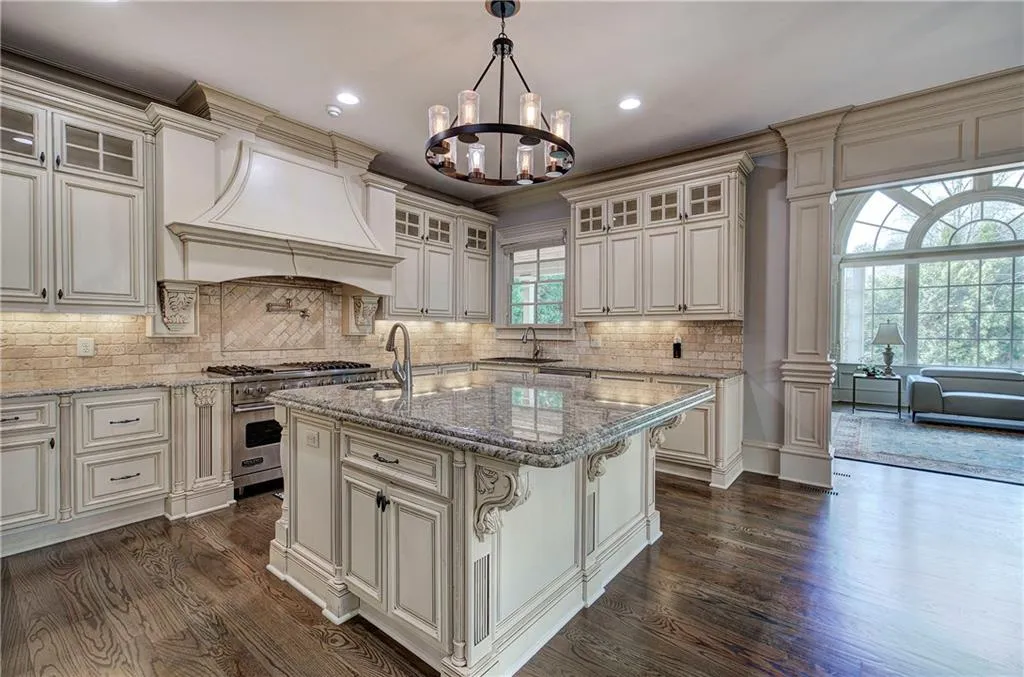 Kitchen featuring glass insert cabinets, light stone countertops, dark wood-style floors, an island with sink, and recessed lighting