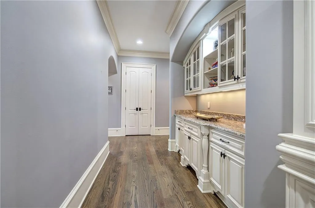 Hallway featuring arched walkways, crown molding, dark wood finished floors, and recessed lighting