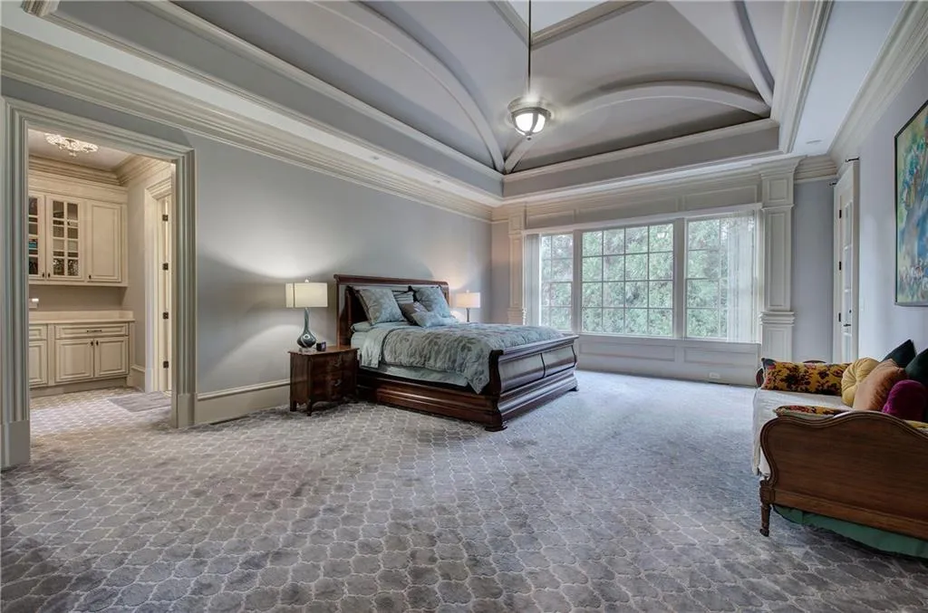 Bedroom with crown molding, lofted ceiling, a tray ceiling, ensuite bathroom, and dark carpet