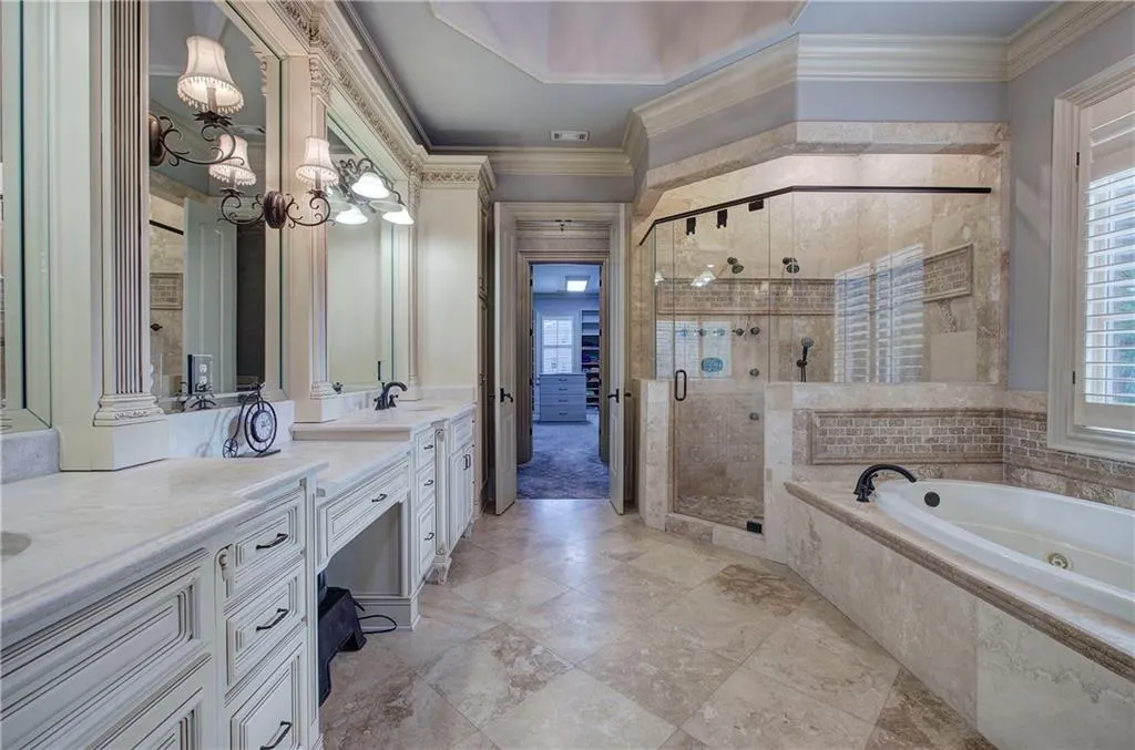 Full bath with vanity, a jetted tub, crown molding, a shower stall, and a chandelier