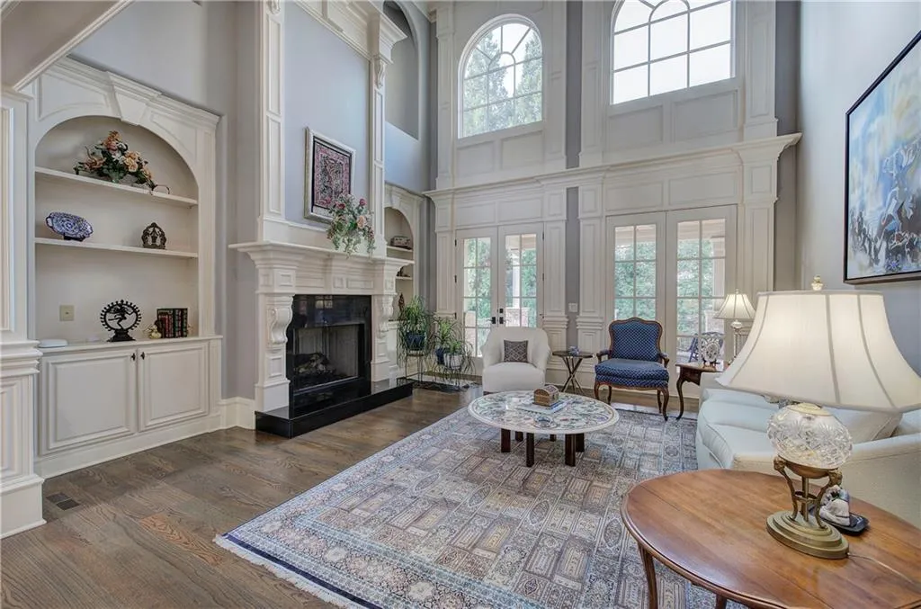 Living area with a towering ceiling, built in shelves, dark wood finished floors, and a fireplace