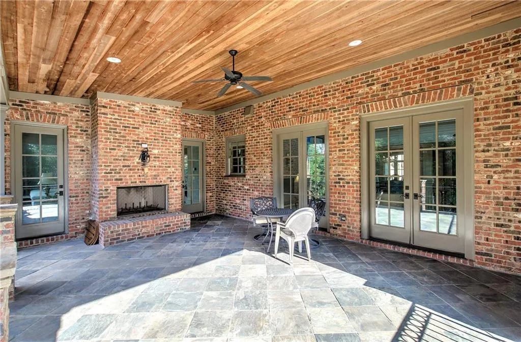 View of patio / terrace with an outdoor brick fireplace, ceiling fan, and french doors