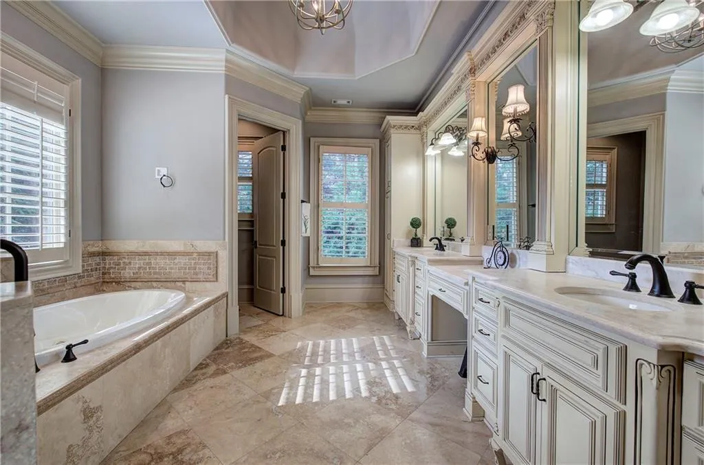 Bathroom featuring a chandelier, double vanity, a garden tub, and crown molding