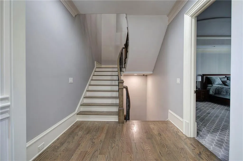 Stairs with wood finished floors and crown molding