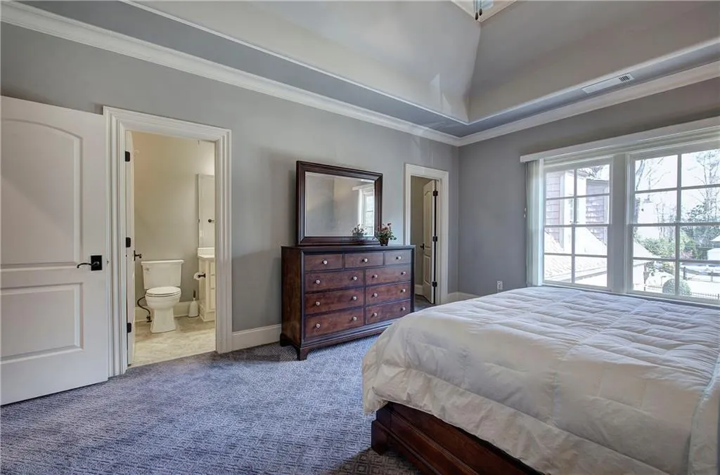 Carpeted bedroom with ornamental molding and ensuite bath