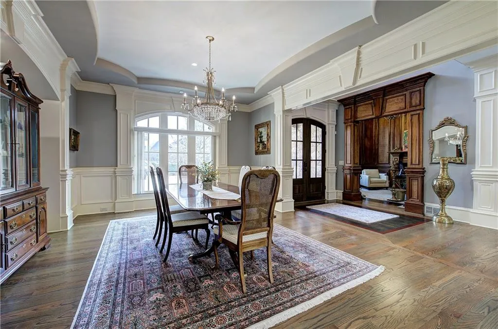 Dining area featuring decorative columns, a tray ceiling, a decorative wall, hardwood / wood-style floors, and ornamental molding