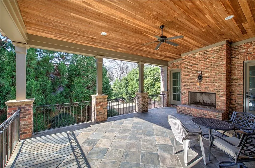 View of patio with an outdoor brick fireplace and ceiling fan