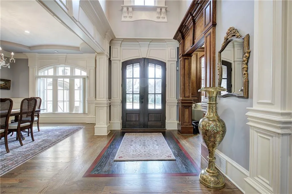 Foyer with a decorative wall, french doors, dark wood-style floors, a chandelier, and arched walkways