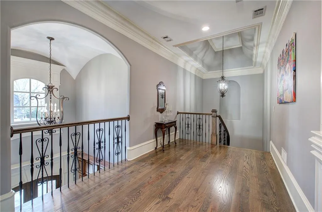 Hallway featuring a chandelier, an upstairs landing, crown molding, and wood finished floors