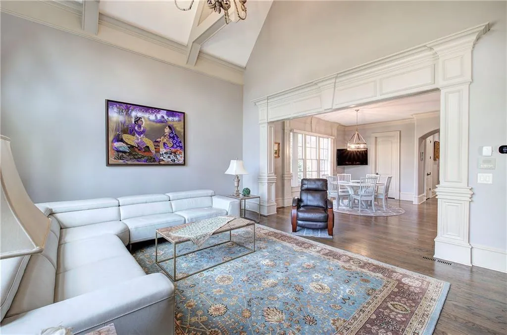 Living area with a chandelier, arched walkways, high vaulted ceiling, dark wood-style floors, and beamed ceiling