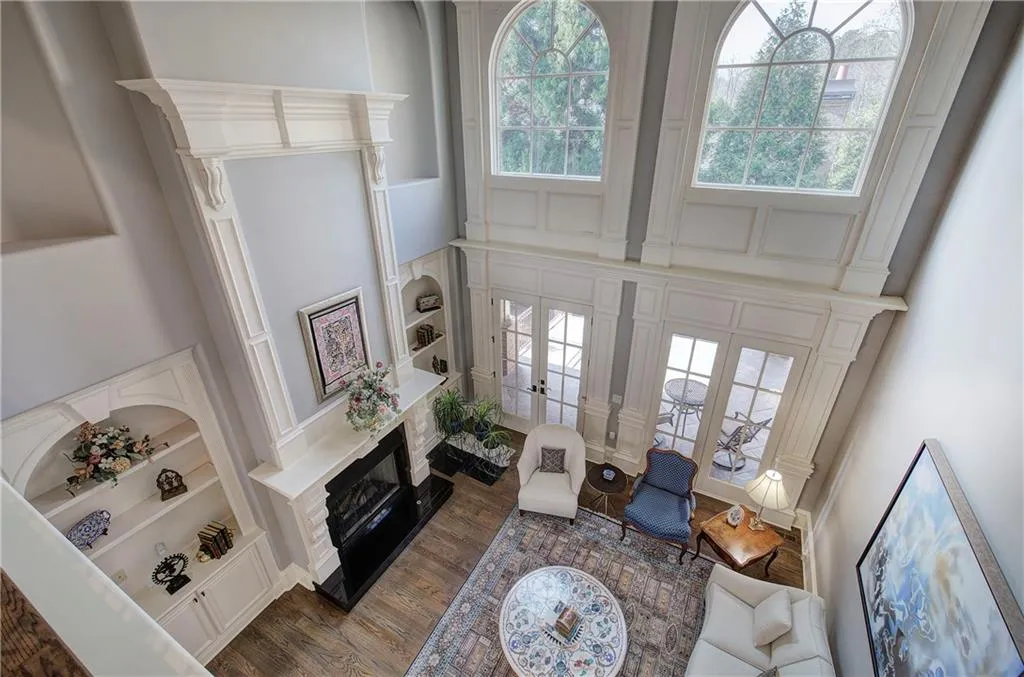 Living room featuring a high ceiling, plenty of natural light, a fireplace, built in features, and dark wood-style flooring