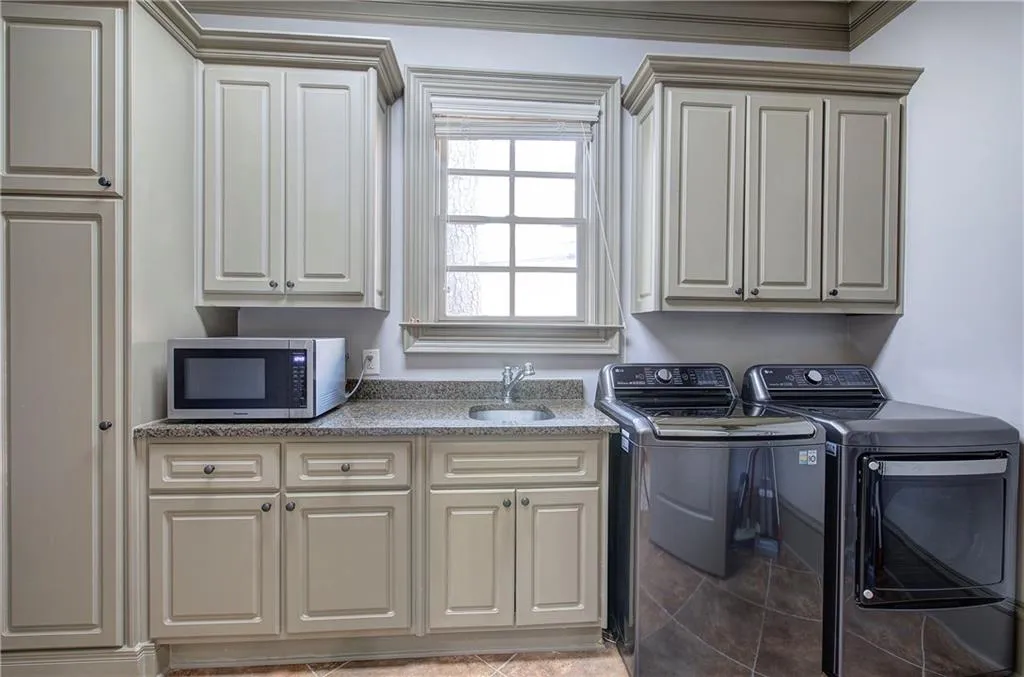 Laundry area featuring washer and dryer, cabinet space, and light tile patterned floors