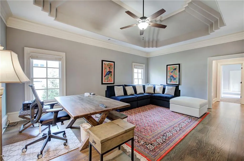 Living area with a desk, wood finished floors, ceiling fan, crown molding, and a tray ceiling