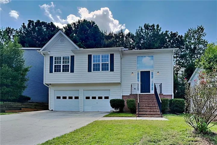 Two-story exterior with light-colored siding, a prominent front entry with a dark door, and a two-car garage