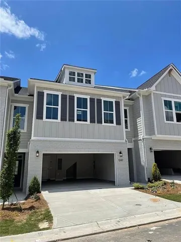 Modern exterior featuring a dormer window, board and batten siding, brick facade, a two-car garage, and concrete driveway