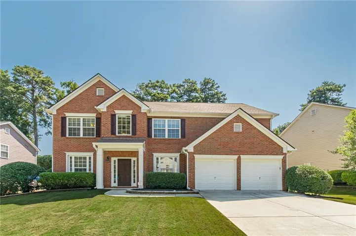 Brick exterior, white window trim, dark window shutters, covered entry with columns, and an attached two-car garage
