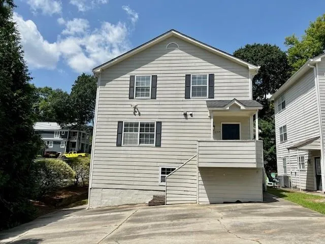 Multi-story residence featuring horizontal siding, multiple windows with dark shutters, and a covered entry