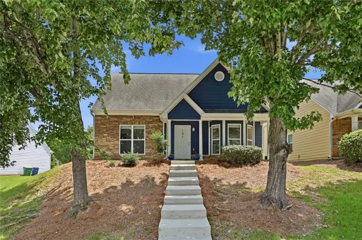 Exterior featuring blue siding, stone facade, a gabled roofline, and a concrete walkway