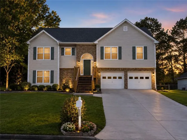 Two-story residence featuring siding and brick accents, an arched entry, a prominent two-car garage, and a concrete driveway