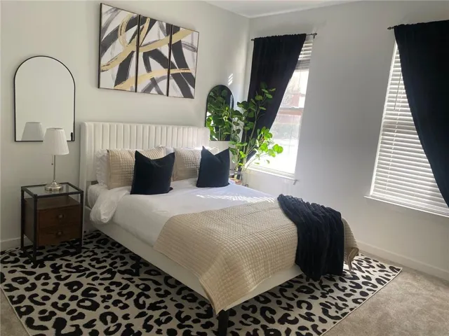 White upholstered headboard with vertical channel tufting, dual windows with white blinds, and a built-in ceiling light fixture