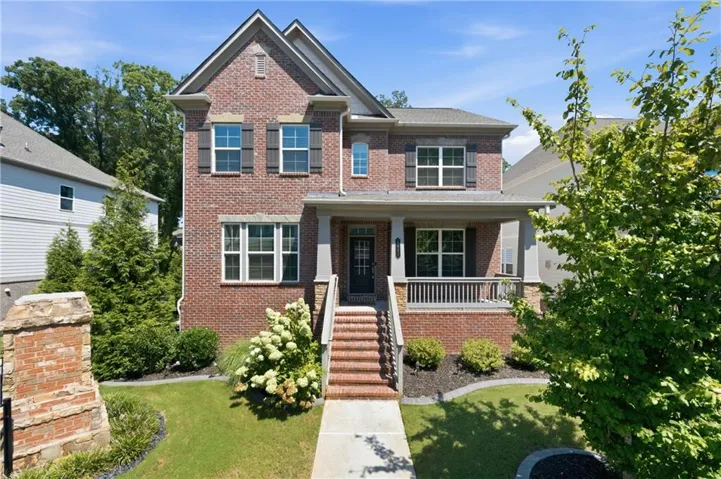 Traditional brick exterior with a covered porch, dark window shutters, and a well-maintained lawn