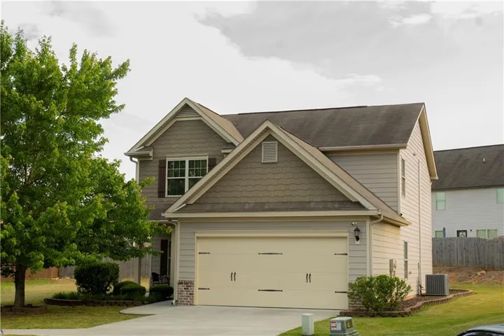 Two-story residence featuring a two-car garage with decorative hardware, a covered entry, and a combination of shingle and siding exterior finishes