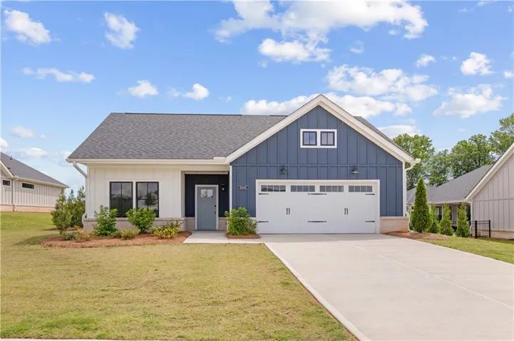 Modern ranch-style home featuring a two-tone facade, a two-car garage with carriage-style doors, and a concrete driveway