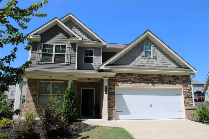 Two-story exterior with a stone and brick facade, gabled roofs, a two-car garage, and landscaped front planting beds