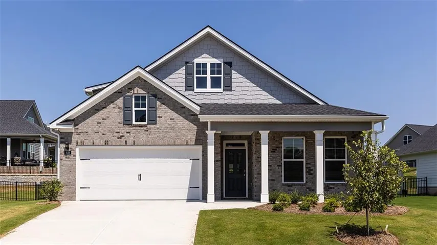 Brick and shake siding exterior with a covered porch, two-car garage, and a gabled roofline