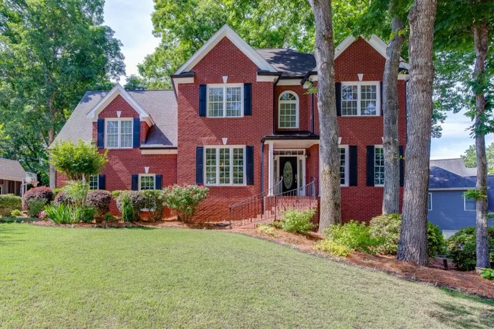 Beautiful brick front home in Dacula, Georgia featuring mature landscaping, a professionally maintained yard, and timeless curb appeal on a spacious homesite near the sought after Hebron Private School and Dacula Schools