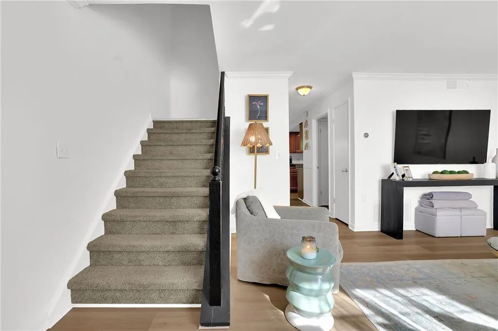 Stairway with wood finished floors and ornamental molding